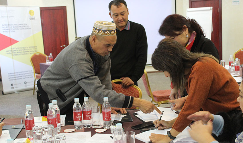 Group of men and women gathered around a table during a seminar for initiative groups on project writing