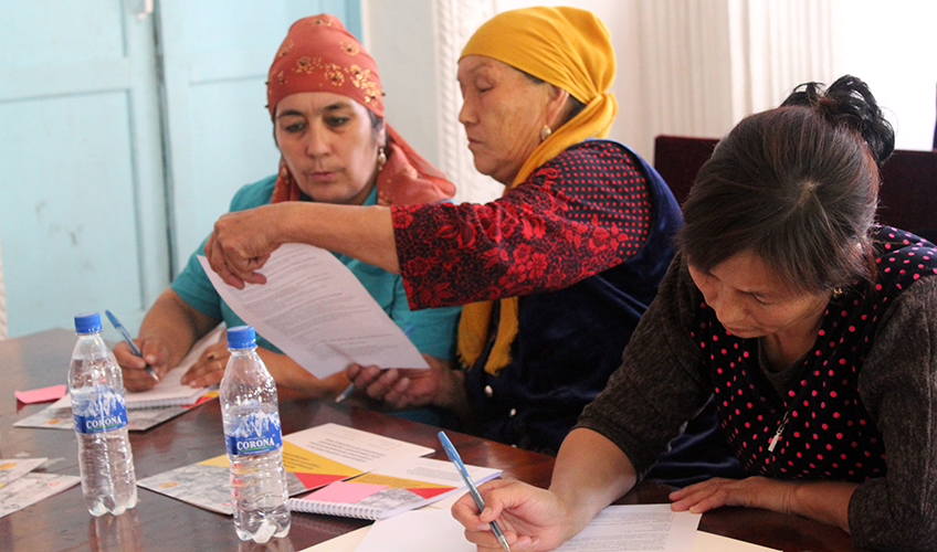 Women gathered around a table writing and discussing what they've written