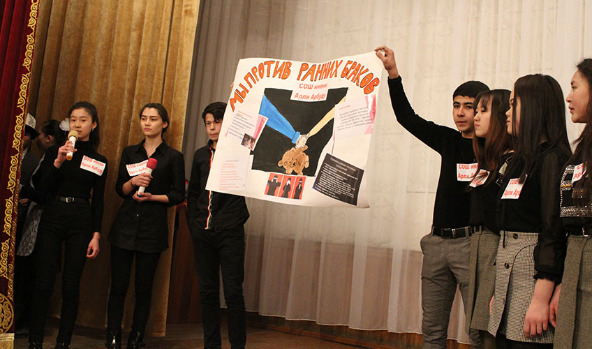 Young women hold up a poster during a presentation