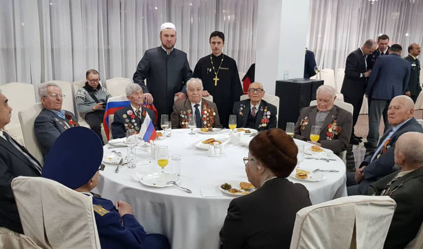 Imam Muhammad Durgalov interacts with a group of men.