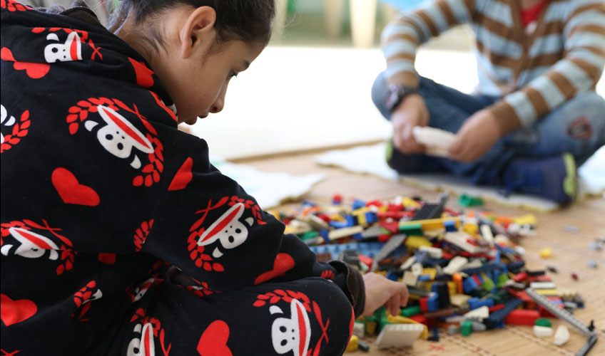 Children play on the floor with colourful lego.