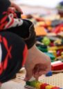 Children play on the floor with colourful lego pieces.