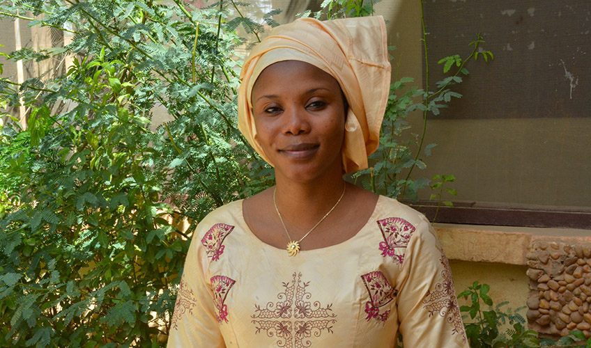 A woman wearing a pale yellow and maroon embroidery. 