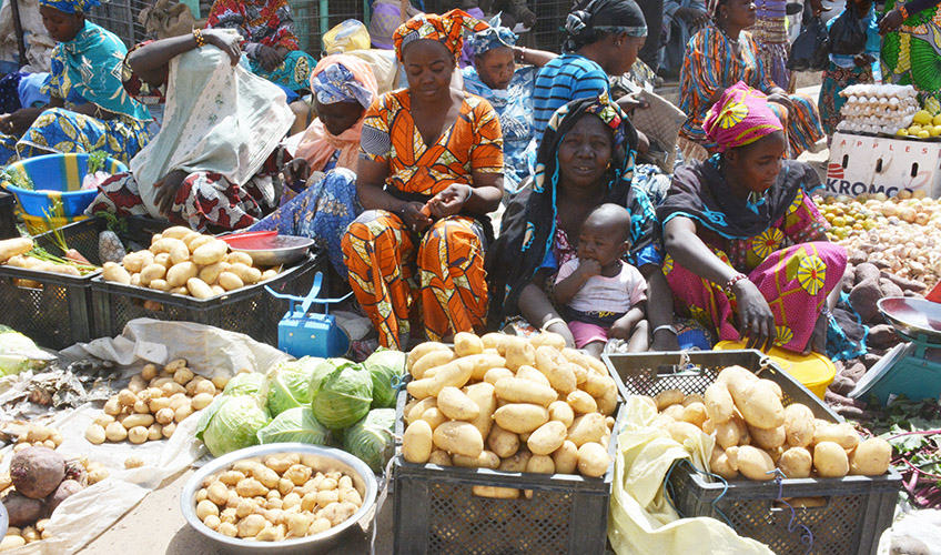 Women at a market stall with potatoes.