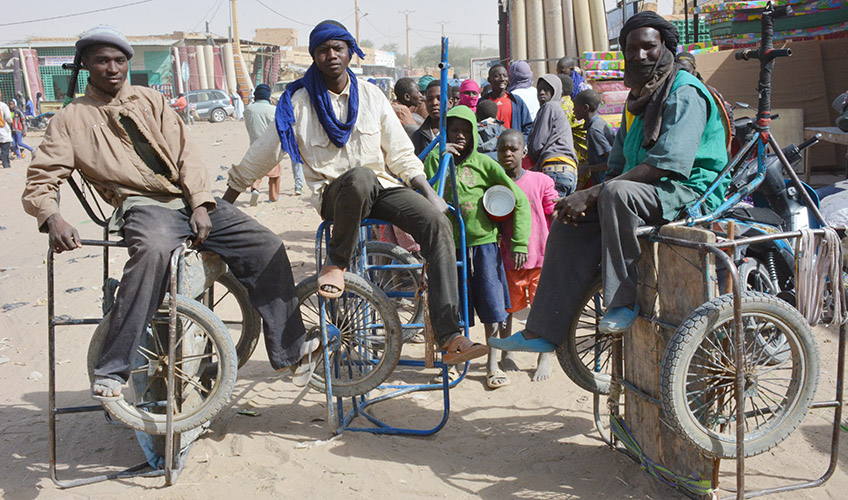 Three men on seats with bicycle wheels.