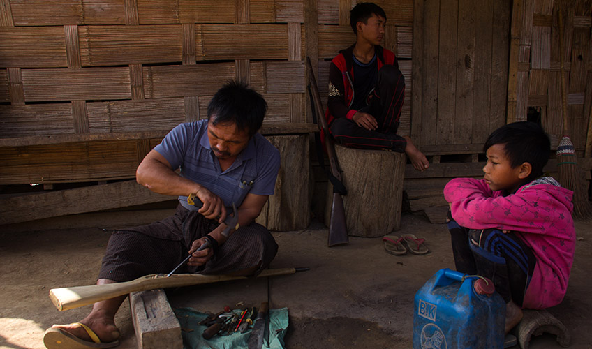 A man carves a rifle stock for hunting in Shan state.