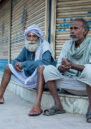 Two men sitting on a step outside a shop in Nepal