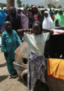 Young children and women gather around a disused car