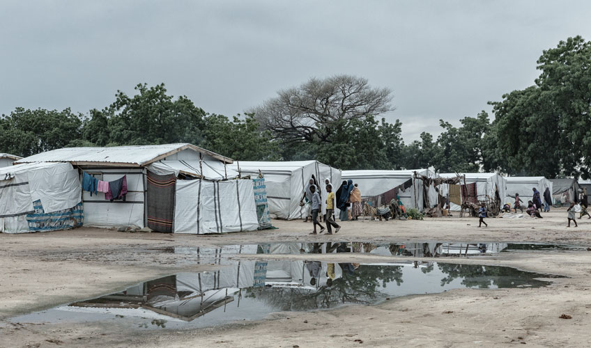 A displacement camp with white tents along a pathway.