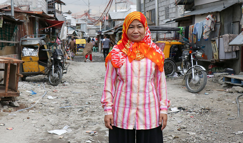 A woman stands in the slums in the Philippines.