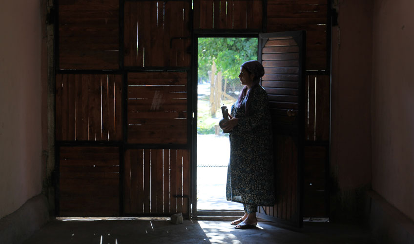 A woman stands silhouetted in a doorway,looking outside