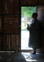 A woman stands silhouetted in a doorway,looking outside