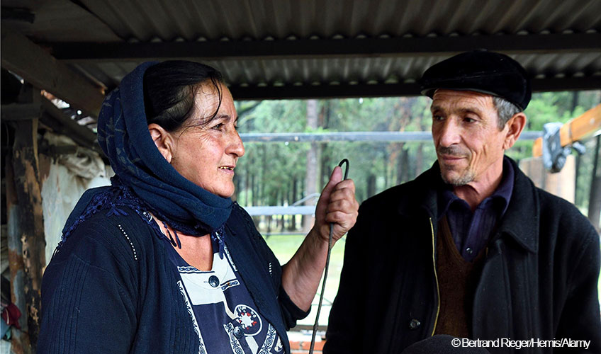 A woman and man stand at a stove cooking.