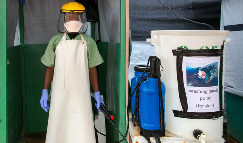 A sprayer wearing protective equipment stands at the entrance of an Ebola treatment unit in Monrovia, Liberia