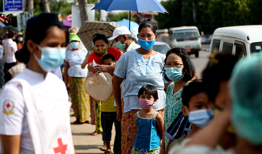 People wait at a COVID-19 health check station in Yangon, Myanmar