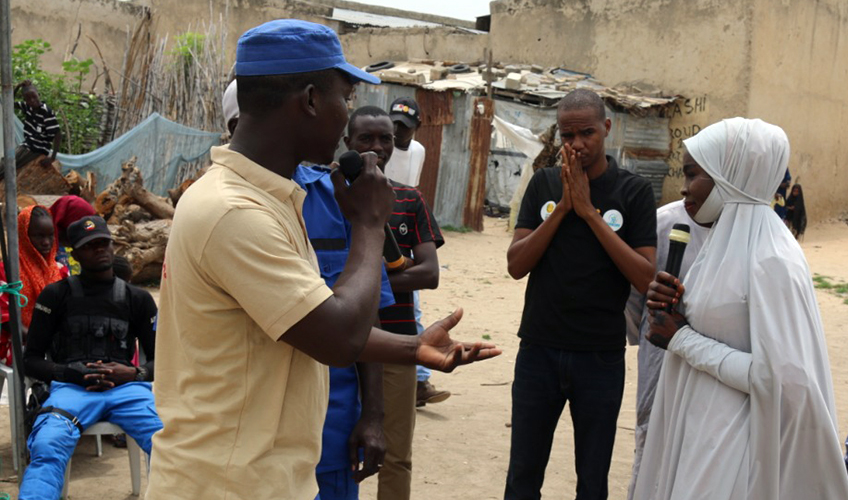 Auwalu and colleagues stand in a group talking as part in a training at Teachers displacement camp