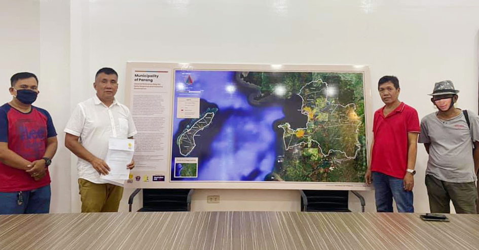 Local chief executives in Lanao del Sur and Maguindanao. Four men stand to the left and right of map in front of a large conference table.