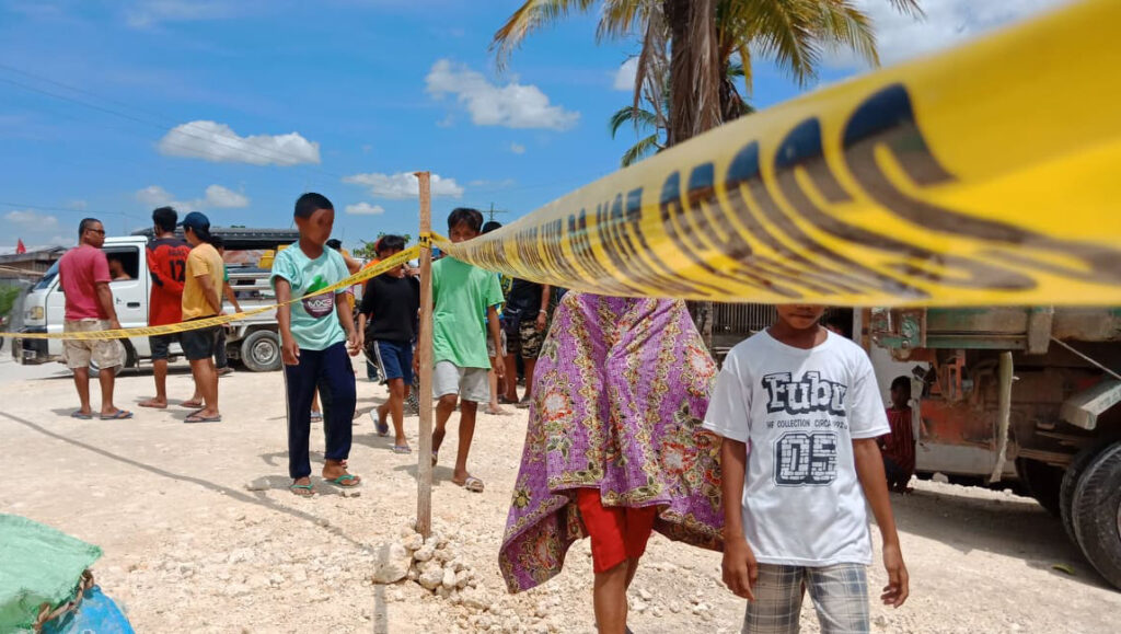 People walking on the beach by a police tape line. 