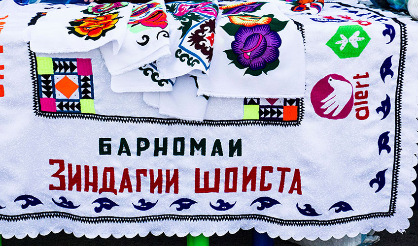 Colourful embroidered cloths of a variety of designs laid on the table for sale