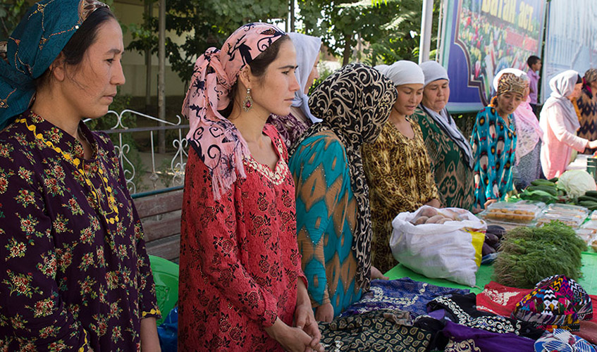 Women stand bheind a table laden with products they have made in their small family-based enterprises as part of the Living with Dignity project