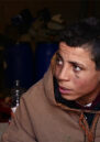 Close up photo of a young man in a brown jacket looking off-camera