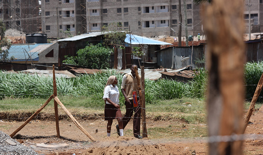 Image shows a man and a woman walking in Kibera Slum.