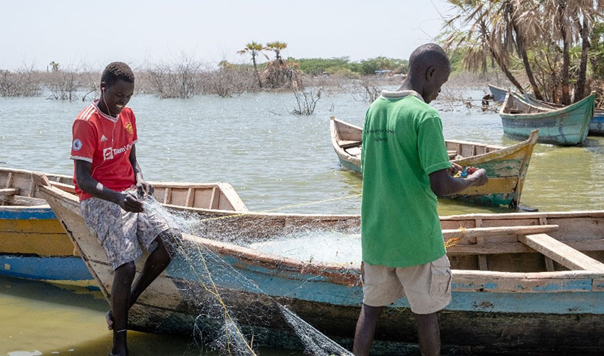 Two fishermen preparing their nets before going out to fish at Impresa beach in Kalokol town.