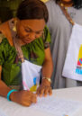 Mme Zawadi Mambo Albertine signing a document.