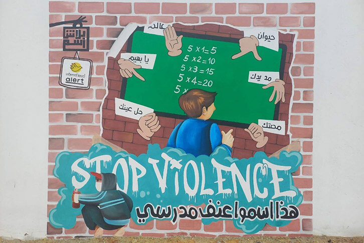 A graffiti work depicts a child in school being shouted at. Underneath an illustrated graffiti artist writes 'Stop violence' in English and Arabic.