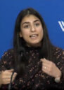 A woman gestures as she speaks to an audience