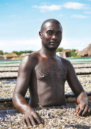 A man inspects mukene (silver) fish drying in the sun. WALUKUBA, BULIISA DISTRICT