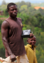 A young man holds a radio on a rural street in the Southern Province of Rwanda.