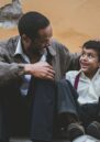 Image shows a man and a young boy. The man has his arm around the child. They are both smiling.